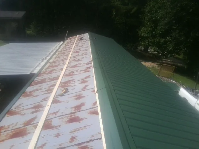 Old rusted panels beside newly installed green metal roofing — Wind Damage Roof Repair by Roofing Brothers in Saint Charles